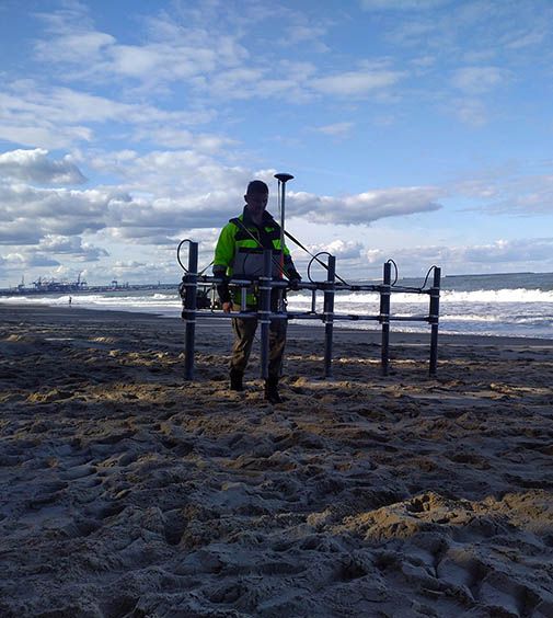 Pracownik firmy saperskiej i wyburzeniowej EXplosive rozkłada sprzęt na morskiej plazy.